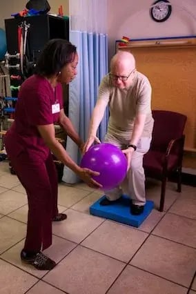 Physical Therapist Handing Exercise Ball To Patient